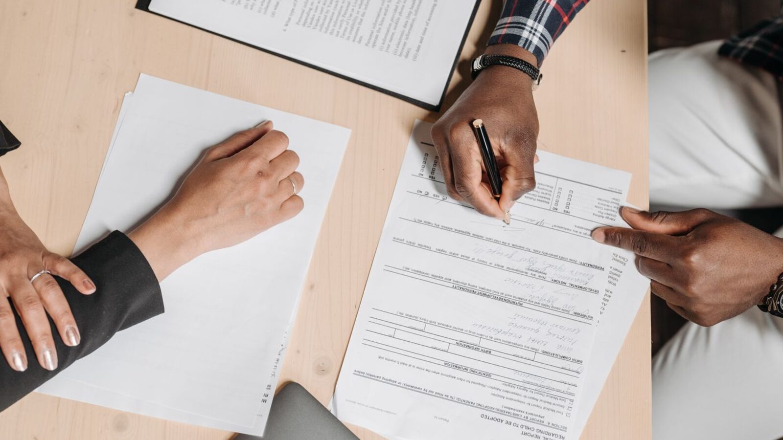 Two people working through paperwork together at a desk